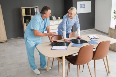 Klinikteki masada röntgen görüntülerini inceleyen olgun doktorlar.