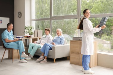 Kliniğin penceresinin yanındaki röntgen görüntüsü üzerinde çalışan kadın doktor