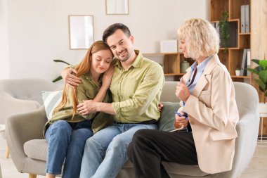 Genç çift psikologun ofisinde kanepede sarılıyor.