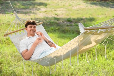 Dışarıdaki hamakta limonatalı genç adam dinleniyor.