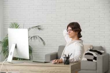 Ofiste bilgisayarla çalışan gözlüklü bir erkek programcı.