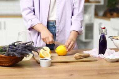 Mutfaktaki masada lavantalı limonata hazırlamak için limon kesen genç bir kadın.