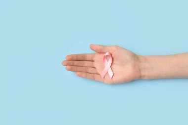 Mavi arka planda pembe ipek kurdeleli bir kadın. Göğüs kanseri kavramı