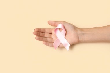 Bej arka planda pembe ipek kurdeleli bir kadın. Göğüs kanseri kavramı