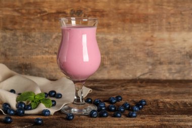 Bir bardak taze böğürtlenli, naneli meyve püresi ve ahşap arka planda böğürtlenler.