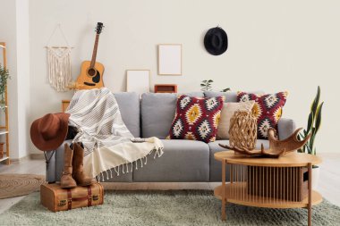 Oturma odasının içinde kanepe, kovboy şapkası ve çizmeleri var.