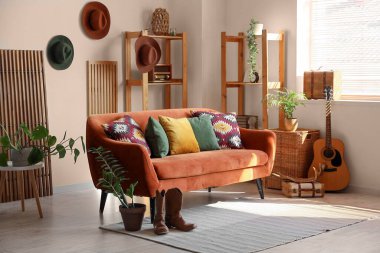 Oturma odasının içinde kanepe, kovboy şapkası ve botları var.