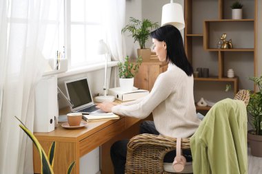 Ev ofis masasında laptop ile çalışan genç kadın