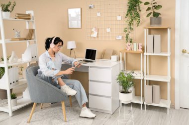 Ofisteki masada tablet bilgisayarla çalışan genç bir kadın.