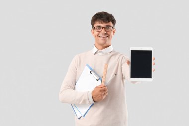 Açık arkaplanda panoları ve tablet bilgisayarı olan erkek matematik öğretmeni