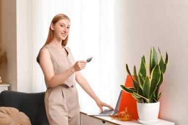 Evde kredi kartı ve dizüstü bilgisayar alışveriş online genç kadın