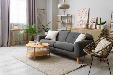 Oturma odasının içinde kanepe, koltuk ve penceresinde perdeler var.