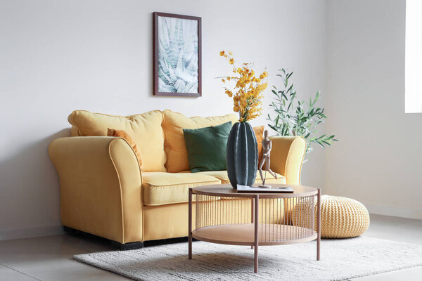 Interior of living room with sofa and artificial flowers on table