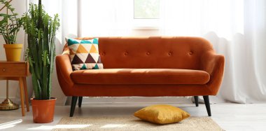 Odanın içinde yeşil bitkiler olan şık bir kanepe.