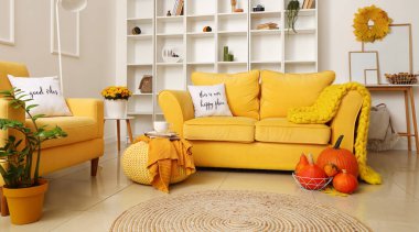 Sarı kanepeler ve balkabaklarıyla modern oturma odasının içinde.