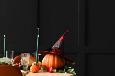 Cadılar Bayramı masa ayarı, balkabakları ve koyu arkaplanda yanan mumlar.