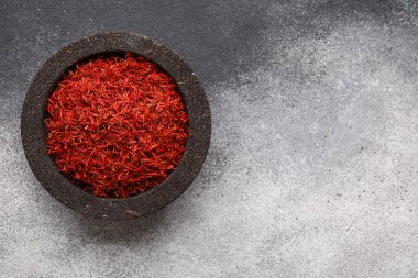 Gri arkaplanda safran yığını olan bir kase.