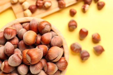 Sarı arka planda kabuklu fındıklı yemek ve kase.