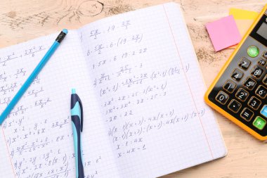 Matematik formülleri, hesap makinesi ve bej ahşap zemin üzerine kırtasiye defteri