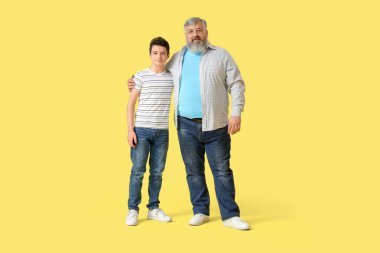 Sarı arka planda sevimli torunu olan mutlu büyükbaba.