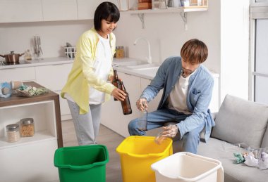 Mutfaktaki çöpleri düzenleyen çöp konteynırları olan genç bir çift. Geri dönüşüm kavramı