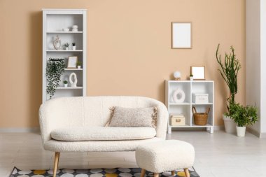 Kanepesi, raf ünitesi ve ev bitkisi olan bej bir oturma odası.