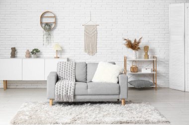 Kanepesi, raf ünitesi ve halısı olan beyaz bir oturma odası.