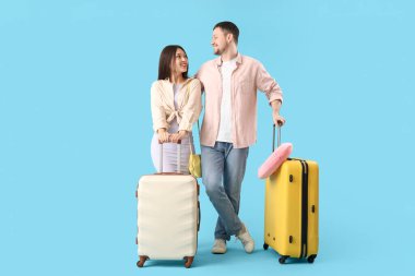 Mavi arka planda bavulları olan genç çift.