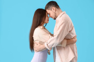 Mavi arka planda sarılan genç çift