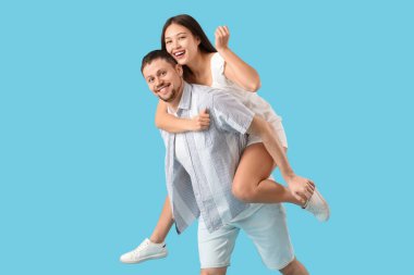 Genç bir adam ve kız arkadaşı mavi arka planda eğleniyorlar.