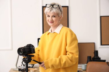 Gözlüklü, şık bir ofiste fotoğraf makinesi olan genç bir kadın.
