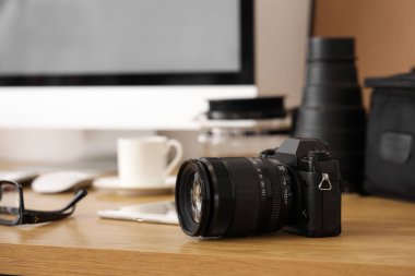 Modern bilgisayarlı şık bir iş yeri ve beyaz duvarın yanında fotoğraf makinesi, yakın çekim.