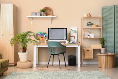 Modern bilgisayarlı ve terzinin ofisindeki bej duvarın yanında renkli iplikleri olan işyeri