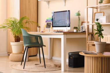 Modern bilgisayarlı ve terzinin ofisindeki bej duvarın yanında renkli iplikleri olan işyeri