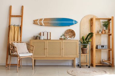 Oturma odasında dekorlu çekmecelerin duvarında ve sandığında sörf tahtası asılı.