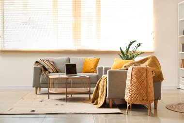 Kahve masasında dizüstü bilgisayarı olan modern oturma odasının içinde.