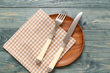 Gri ahşap arka planda tabak, çatal bıçak ve peçete.