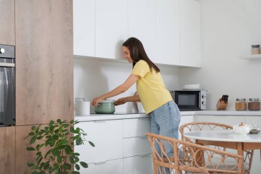 Genç bir kadın modern mutfakta ocağa esrar koyuyor.