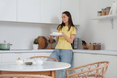 Modern mutfakta tabak yığını olan genç bir kadın.