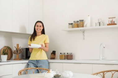 Modern mutfakta tabak yığını olan genç bir kadın.