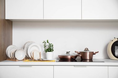 Mutfaktaki beyaz tezgahın yanında farklı temiz bulaşık takımları var.