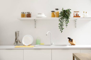 Mutfaktaki lavabonun yanında temiz tabak ve çatal bıçak yığını.