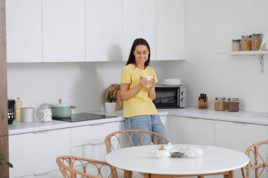 Modern mutfakta fincanı olan genç bir kadın.