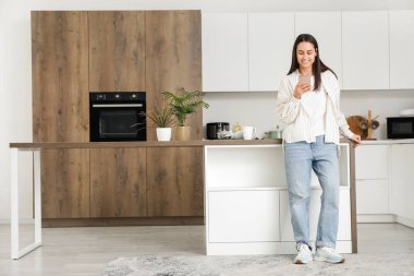 Modern mutfakta cep telefonu kullanan genç ve güzel bir kadın.