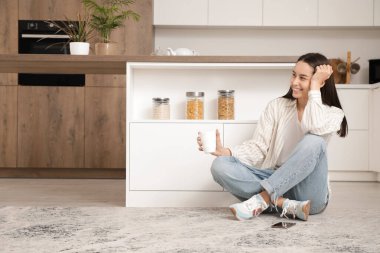 Genç ve güzel, modern mutfakta yerde oturuyor.