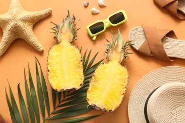 Hasır şapkalı taze ananas, parmak arası terlik, güneş gözlüğü, denizyıldızı ve turuncu arka planda palmiye yaprağı.