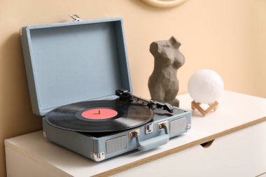 Odadaki bej duvarın yanındaki klozette disk ve ev dekoruna sahip kayıt çalar