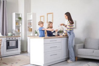 Annem mutfakta çocuklarına süt dolduruyor.