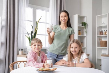 Mutfaktaki yemek masasında süt içen mutlu aile.