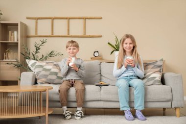 Süt ve kurabiyeli çocuklar oturma odasında kanepede oturuyorlar.